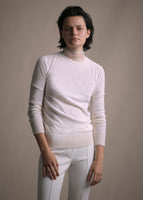 Cropped image of a model facing forward wearing white crewneck sweater and white pants