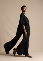 Side profile of the model wearing the Cape Back Gown in Silk Crepe in Black.