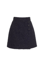Flat lay of short black wrap skirt with three black buttons in metallic tweed.