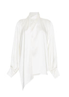 Flat lay of an ivory long sleeve silk charmeuse blouse with an asymmetrical wrap front.