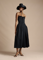 A model wearing the Rickie Dress in Satin Suiting, paired with the Taiko Hat in Black.