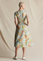 A model standing backwards wearing a pale blue floral fit and flare short sleeved, mid length dress.