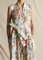 A close-up image of a white floral sleeveless jumpsuit with a fabric belt tied at waist.