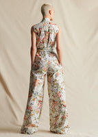 A model stands backwards wearing a white floral sleeveless jumpsuit 