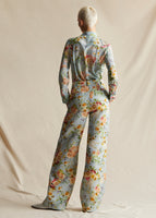 Model standing backwards wearing a pale blue floral wide leg pant, with a matching pale blue floral long sleeved shirt.