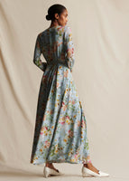 Model standing backwards wearing a pale blue floral, long sleeved, maxi dress.