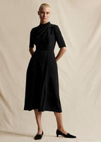 A model wears a black mid length short sleeved dress.