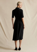 A model standing backwards wearing a black mid length short sleeved dress