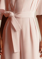 A close-up of pleats and fabric belt on a model.