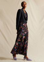 Model wearing a black cropped jacket, over a long  black pleated floral dress.