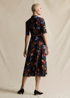 A model standing backwards wearing a black ground floral midi dress