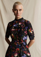 A close-up from the waist of a model wearing a black ground floral short sleeved dress