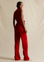 A model standing backwards wearing a red sleeveless jumpsuit.