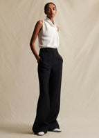 An image of a model wearing an ivory sleeveless silk top tucked into black pants.
