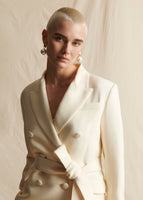 Close up image of a model wearing an ivory double breasted belted blazer.