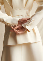 A close-up image of the cuffs of an ivory blazer with 6 buttons on each cuff