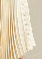 Close up image of ivory pleated skirt showing pleating detail and buttons.