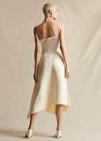 Model standing backwards in an ivory cami top tucked into an ivory mid length skirt.