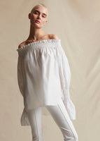 Model wearing a white off the shoulder top, with white pants