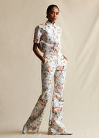 A model wearing a white floral flare pant, styled with a white floral short sleeved collared top. 