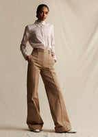 A model stands wearing a khaki wide leg pant with pintuck on the front and cuffed hem. Styled with a red and white striped shirt.