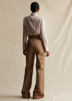 A back view of a model standing wearing a khaki wide leg pant with cuffed hem. Styled with a red and white striped long sleeve shirt.