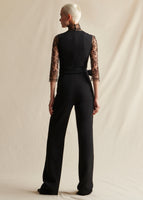 A model standing backwards wearing a black sleeveless jumpsuit.