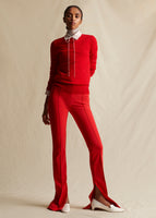 A model facing forwards wearing a red crewneck sweater with red pants and white shoes.