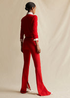 A model standing sideways wearing a red sweater and red flare pants.