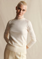 Model wearing an ivory crewneck sweater over an ivory lace turtleneck. 