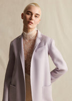 A model wearing a lilac coat, with an ivory lace turtleneck underneath.