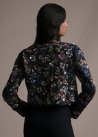 Back-facing image of a model wearing long sleeve front-zip multicolor flower embroidered black bolero.