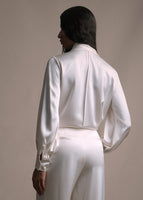 A back-facing image of a model wearing long sleeve silk charmeuse blouse in ivory with matching pants. 