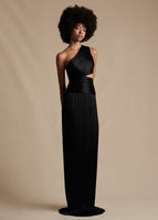 Model is wearing the one-shoulder Delphos Dress in Charmeuse. It is a black, floor-length dress with a cut-out on the wearer's left side.