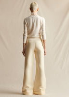 Model standing backwards wearing an ivory crew neck sweater and ivory wide leg pants.