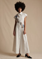 Model is wearing the short-sleeve Dejeuner Dress in Embroidered Poplin. An embroidered floral pattern goes from the right shoulder down to the waist.