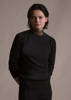 Image of a model facing forwards wearing black crewneck sweater.