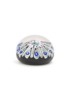 Photo of Millefiori glass paperweight with intricate pattern containing blue, green, and light pink colors.