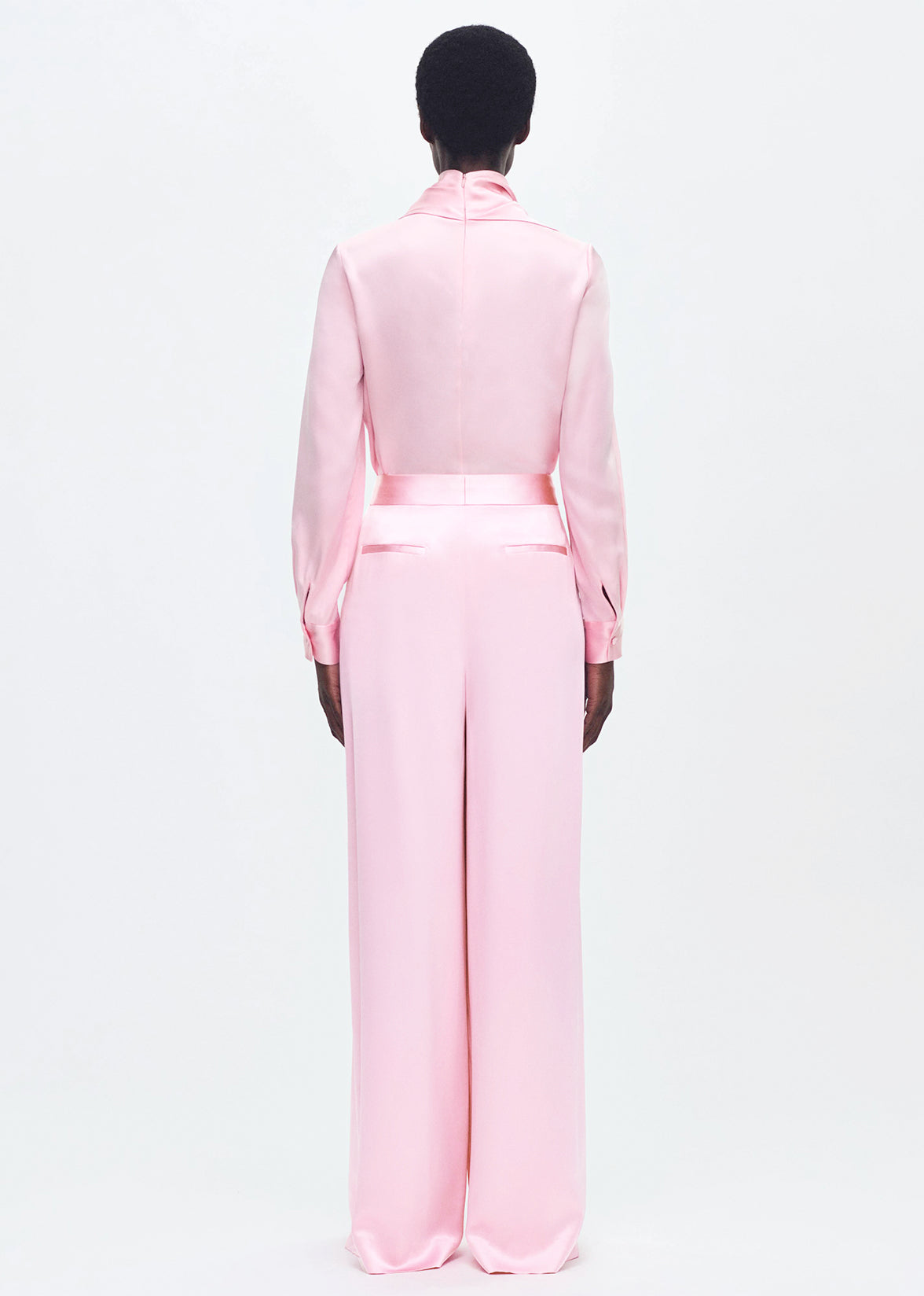 Back-facing model wearing the nils pant in pink silk charmeuse