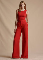 Model stands forward wearing a red sleeveless knit top tucked into red long trouser pants..