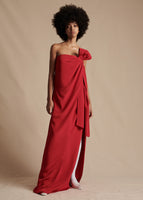 Model is wearing the red Bustier Dress in silk Crepe. Featuring a bow on the wearer's left shoulder as well as a side slit.