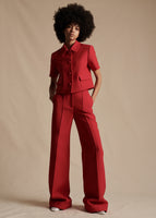 Model stands forward wearing a red short sleeved blazer with red wide leg trousers.