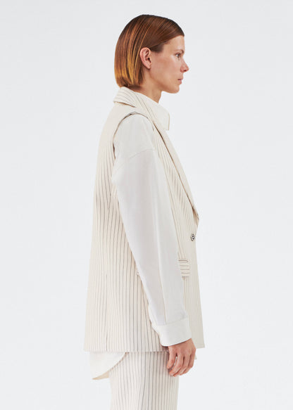 side view of model wearing the callen vest by adam lippes in pinstripe twill layered over a top 