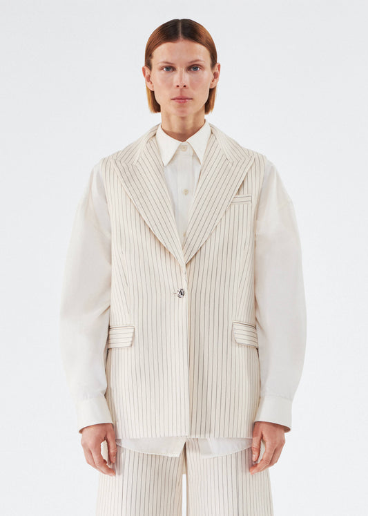 model wearing the callen vest by adam lippes in pinstripe twill layered over a top 