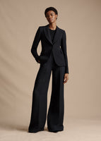 An image of a model facing forward wearing a black single breasted blazer and black wide leg pants.
