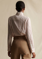 An image from behind of a model wearing a red and white striped shirt tucked into khaki pants. 