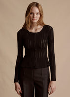 Model is wearing the black Cardigan with Peplum in Pointelle Knit and matching black trousers.