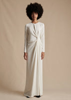 Model is wearing the long-sleeve, floor-length white Long Draped Dress in Silk Crepe. The dress features a knot on the wearer's left side.