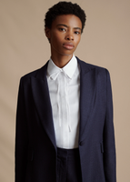 A close up of a model wearing the Single Breasted Blazer in Stretch Canvas, paired with the Full Leg Trouser in Stretch Canvas and the Shirt with Thin Bow.