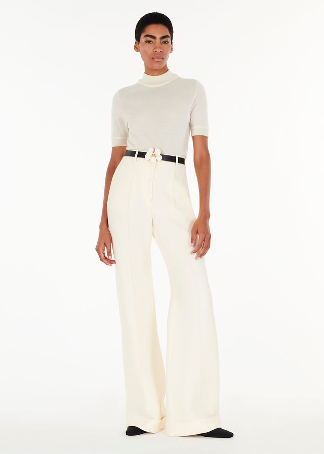 full body front-facing model wearing the deeda pant in silk wool with the mockneck in ivory and rose flower belt